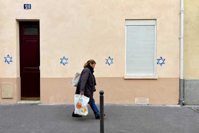  A woman walks past a building tagged with Stars of David in Paris, France, October 31, 2023 (credit: REUTERS/LUCIEN LIBERT)