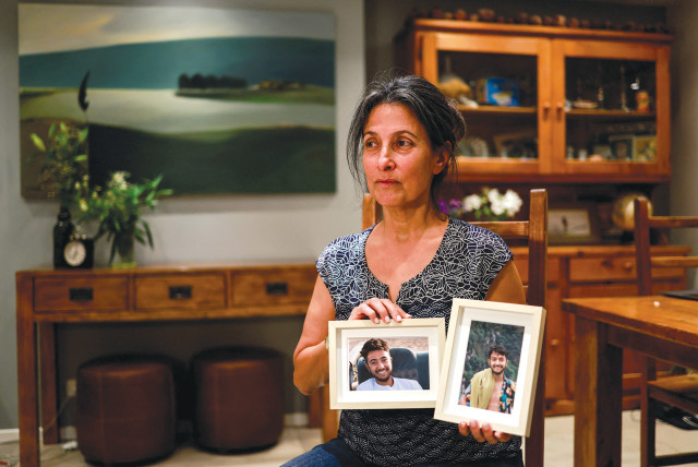 Rachel Goldberg, the mother of Hersh Goldberg Polin, who was taken hostage by Hamas terrorists while attending a music festival in southern Israel, holds photographs of her son in their home in Jerusalem on October 17 (credit: AMMAR AWAD/REUTERS)