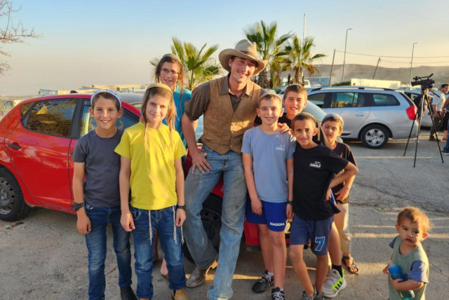  Kids in Judea and Samaria pose for pictures with American cowboys who came to lend a hand. (credit: HAYOVEL)