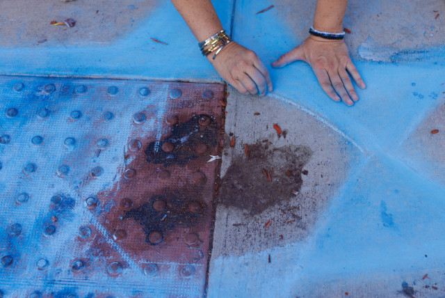 Chalk drawer Elena Colombo of the Hamakom Synagogue draws a blue star around blood at the exact location on the sidewalk of the alleged assault on Paul Kessler on Sunday in Thousand Oaks, California, U.S., November 7, 2023. (credit: MIKE BLAKE/REUTERS)