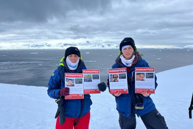 Marine biologists Prof. Tali Mass (left) and Dr. Tal Luzzatto Knaan show posters of Israelis kidnapped by Hamas on October 7. Antarctica, 2023. (credit: Courtesy)
