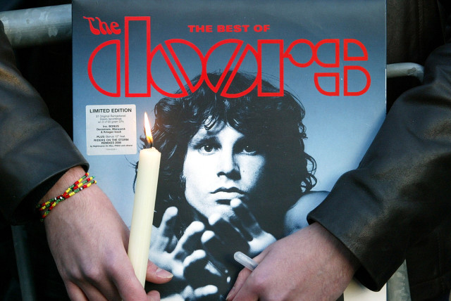  A fan holds an album by the seventies rock group The Doors and a candle near the tomb of late singer Jim Morrison during a ceremony marking what would have been Morrison's 60th birthday at the Pere Lachaise cemetery in Paris, December 8, 2003.