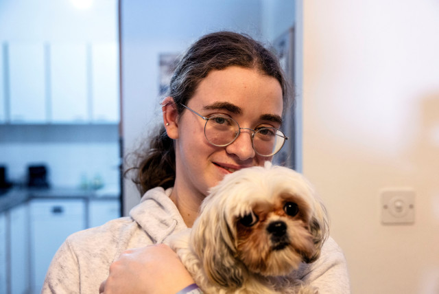 Mia Leimberg, 17, released from captivity after being taken hostage by Hamas in the Gaza Strip with her mother Gabriela and her dog Bella, holds the dog in her arms at their home in Jerusalem, December 5, 2023. Mia's uncle and aunt's partner remain in captivity. (credit: REUTERS/Ronen Zvulun)