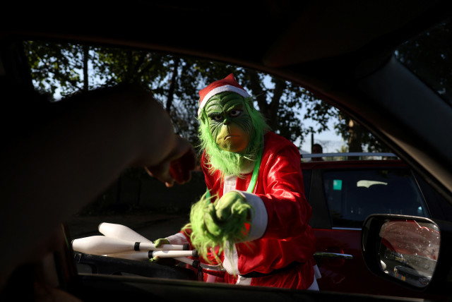 A person dressed as the Grinch stands next to a car, during Christmas season in Santiago, Chile, December 20, 2023. (credit: IVAN ALVARADO/REUTERS)