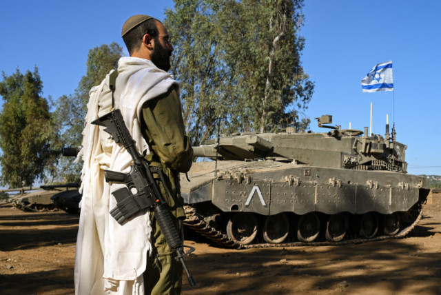  An Israeli soldier with a prayer shawl seen during a morning prayer near his tank near the border with Lebanon, northern Israel, October 25, 2023 (credit: MICHAL GILADI/FLASH90)