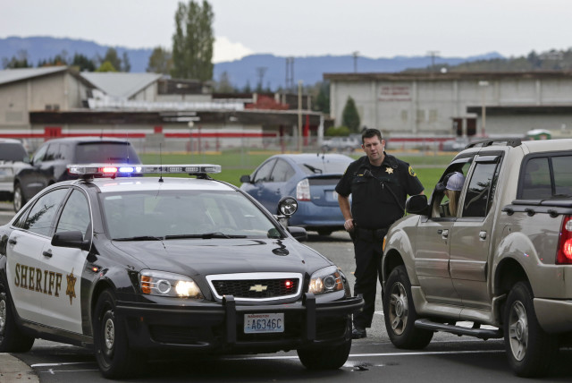  A County Sheriffs deputy stops traffic as police investigate a campus shooting in Marysville, Washington October 24, 2014. (credit: REUTERS/JASON REDMOND)