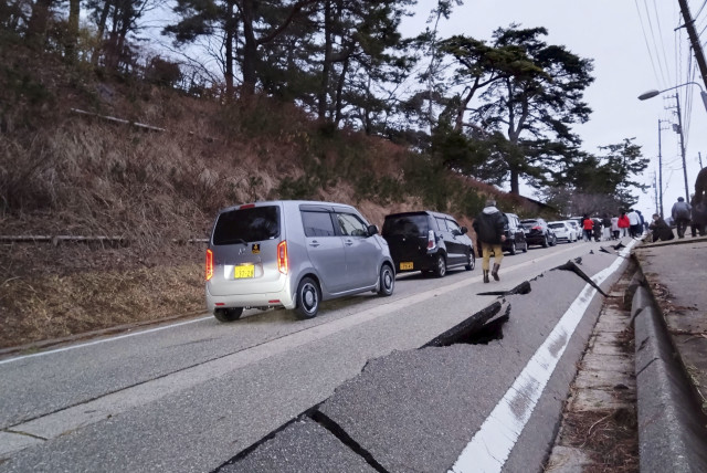  People walk along a road damaged by an earthquake, in Wajima, Ishikawa prefecture, Japan January 1, 2024. (credit:  Kyodo via REUTERS)