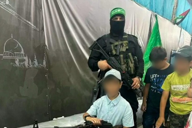  Gazan children poses with weapons and a Hamas terrorist in this photo released by the IDF, January 3, 2023 (credit: IDF SPOKESPERSON'S UNIT)