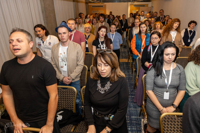  Participants at a Limmud FSU event in Israel amidst the war with Hamas stand for the singing of Hatikvah, Israel's national anthem. (credit: Alexander Khanin via JTA)