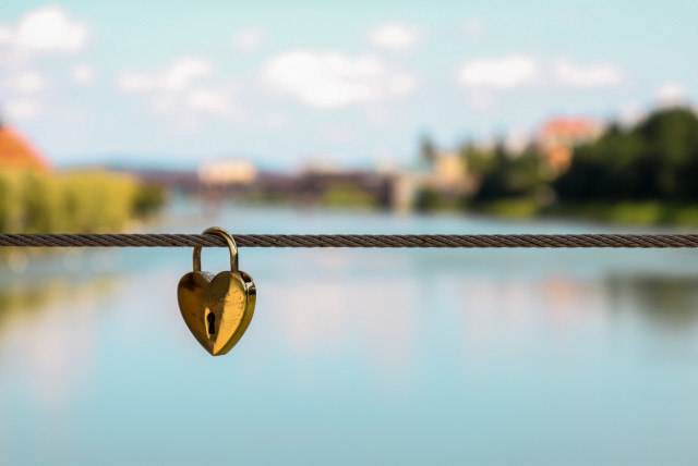 Heart-shaped lock on a rope over a river (Illustrative) (credit: Miha Arh/Unsplash)