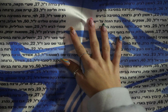 A girl puts her hand on a list of names of Israelis killed since October 7, during a 24-hour protest, in Tel Aviv, Israel, January 13, 2024 (credit: REUTERS/ALEXANDRE MENEGHINI)
