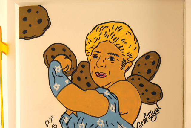  ‘Rachel and the Cookies’ by Grafitiyul, depicts Rachel Edri as Wonder Woman, based on an illustration by Daniel Amit.  (credit: Suzi Bar)