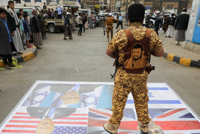 A Houthi policeman stands on a banner with pictures of Benjamin Netanyahu, Rishi Sunak and Joe Biden during a parade by Houthi recruits in a show of force amid a standoff in the Red Sea and US-led airstrikes on Houthi targets, in Sanaa, Yemen, February 8, 2024. (credit: REUTERS/KHALED ABDULLAH)