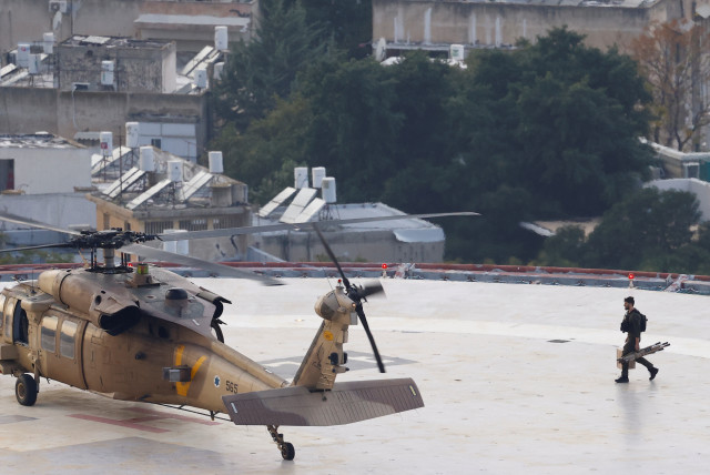  A military helicopter sits on the helipad of the Tel Aviv Sourasky Medical Center (Ichilov) as a soldier returns with an empty stretcher after dropping off an injured soldier (credit: CLODAGH KILCOYNE/REUTERS)