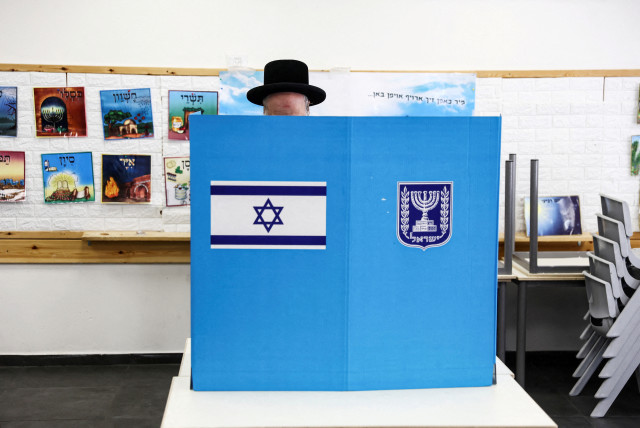  An Ultra-Orthodox Jewish Israeli selects his ballot paper on the day of Israel's general election in a polling station in Jerusalem November 1, 2022. (credit: RONEN ZVULUN/REUTERS)