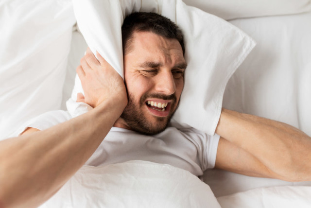  Hombre tumbado en la cama con almohada sufriendo por el ruido (credit: INGIMAGE)
