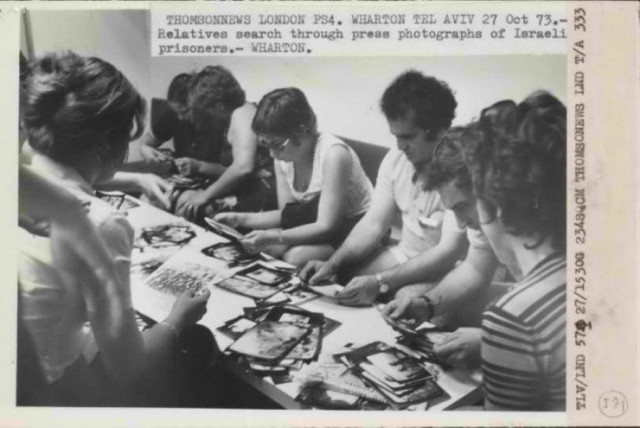 Israelis sift through press photographs looking for their missing loved ones serving in the IDF, October 1973 (credit: NATIONAL ARCHIVES)