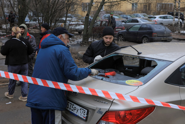 Men remove broken glass from a damaged car following an alleged drone attack in Saint Petersburg, Russia, March 2, 2024. (credit: STRINGER/ REUTERS)
