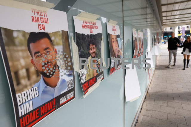  People walk past posters with photos of hostages kidnapped in the deadly October 7 attack on Israel by the Palestinian Islamist group Hamas from Gaza, in Tel Aviv, Israel March 2, 2024. (credit: CARLOS GARCIA RAWLINS/REUTERS)