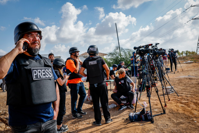 Foreign and Israeli journalists stand on a hill overlooking the Gaza Strip in the city of Sderot, southern Israel, October 19, 2023. ` (credit: NATI SHOHAT/FLASH90)