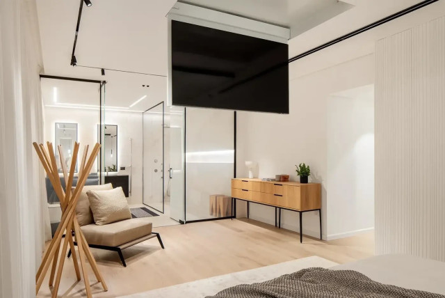   View from the bed towards the bathroom including a retractable TV from the ceiling  (credit: Yoav Peled, Studio Peled)