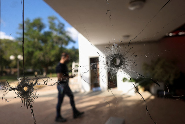  A man walks behind a glass with bullet holes following the deadly October 7 attack by gunmen from Palestinian militant group Hamas from the Gaza Strip, in Kibbutz Nir Oz in southern Israel November 21, 2023.  (credit: RONEN ZVULUN/REUTERS)