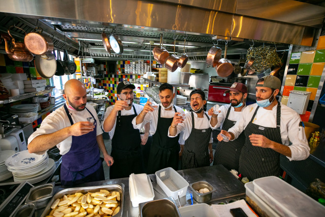  The chef and his staff hold a glass of arak to celebrate the reopenning as they  cook prior to the reopenning of the Machneyuda restaurant on March 07, 2021 in Jerusalem. (credit: OLIVIER FITOUSSI/FLASH90)