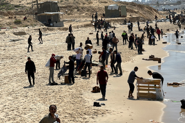  Palestinians gather on a beach as they collect aid airdropped by an airplane, amid the ongoing conflict between Israel and Hamas, in the northern Gaza Strip, March 25, 2024. (credit: REUTERS/STRINGER)