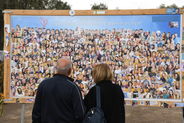  People look at a board featuring the faces of people who lost their lives on October 7. (credit: SETH J. FRANTZMAN)