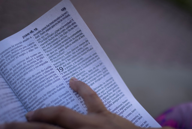  An Ecuadorean migrant reads from a Bible she was given in Mexico where she says she was kidnapped and sexually trafficked near the U.S.-Mexico border as she meets with reporters in New Jersey, U.S., on August 18, 2023. (credit: REUTERS/Maye-E Wong)