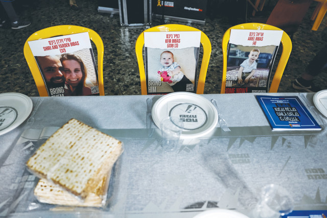  Photos of the Bibas family, held hostage in Gaza, are seen at a Passover ceremony in Kibbutz Nir Oz, on April 11, 2024. (credit: AMIR COHEN/REUTERS)