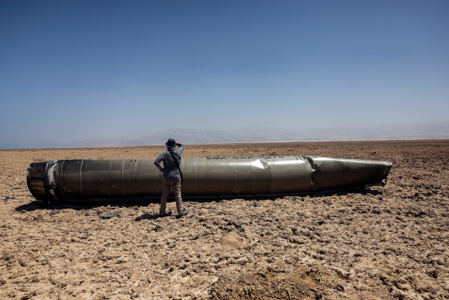  A man stands next to the apparent remains of a ballistic missile, as it lies in the desert near the Dead Sea, following a massive missile and drone attack by Iran on Israel, in southern Israel April 21, 2024  (credit: REUTERS/Ronen Zvulun)