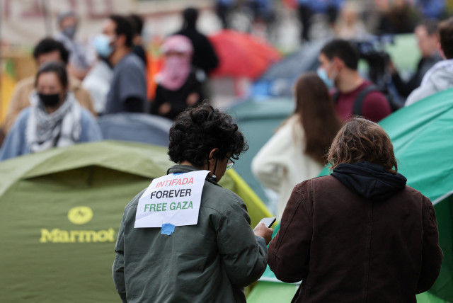  A person with a message attached to their jacket uses a phone, at an encampment where students protest in support of Palestinians, amid the ongoing conflict between Israel and Hamas, at the University of California in Los Angeles, California, US. April 25, 2024. (credit: MIKE BLAKE/REUTERS)