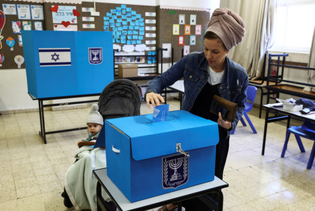  Una mujer israelí deposita su voto el día de las elecciones generales de Israel en un colegio electoral de Kiryat Arba, un asentamiento judío de Cisjordania 1 de noviembre de 2022. (credit: REUTERS/Ronen Zvulun)