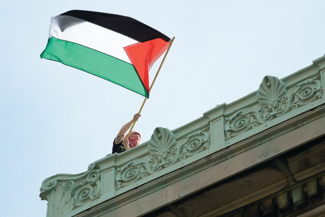  A STUDENT protester waves a Palestinian flag above Hamilton Hall on the campus of Columbia University in New York, in late April. (credit: MARY ALTAFFER/REUTERS)