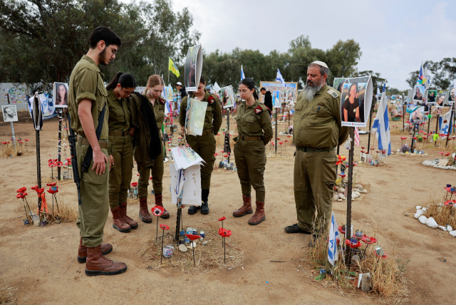  Soldados israelíes permanecen inmóviles durante una sirena de dos minutos que marca el Día de Conmemoración del Holocausto anual israelí, en una instalación en el lugar del festival Nova donde los asistentes a la fiesta fueron asesinados y secuestrados durante el ataque del 7 de octubre por hombres armados de Hamás desde Gaza, en Reim, sur de Israel, 6 de mayo de 2024. (crédito: AMMAR AWAD/REUTERS)