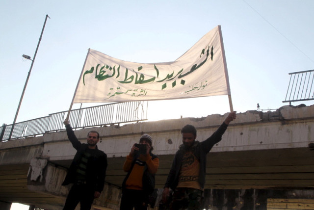  Varias personas portan una pancarta mientras asisten a una protesta contra las fuerzas leales al presidente sirio Bashar al Assad, Rusia y las Fuerzas Democráticas Sirias, en el barrio de Tariq al-Bab de Alepo, Siria 29 de febrero de 2016. (credit: REUTERS/ABDALRHMAN ISMAIL)