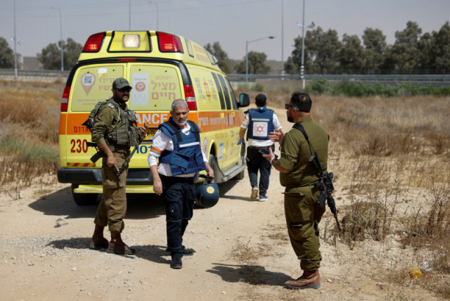  Un médico israelí camina cerca de soldados y una ambulancia después de que Hamás reivindicara un ataque en el cruce de Kerem Shalom, 5 de mayo de 2024. (credit: REUTERS/AMIR COHEN)