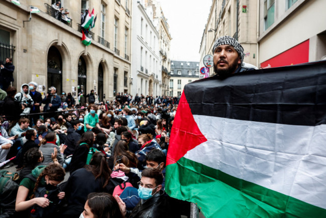  Una persona sostiene una bandera palestina mientras la gente participa en la ocupación de una calle frente al edificio de la Universidad Sciences Po en apoyo a los palestinos de Gaza, durante el actual conflicto entre Israel y el grupo islamista palestino Hamás, en París, Francia, 26 de abril de 20 (credit: REUTERS/GONZALO FUENTES)