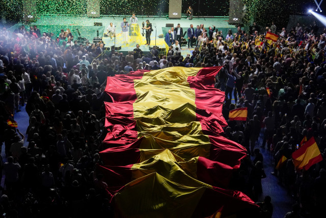 Personas sostienen una bandera española gigante al final de un mitin organizado por el partido ultraderechista español Vox antes de las elecciones europeas, con varios líderes de extrema derecha, entre ellos el presidente de Argentina, Javier Milei, en Madrid, España, 19 de mayo de 2024.  (credit: REUTERS/Ana Beltran)