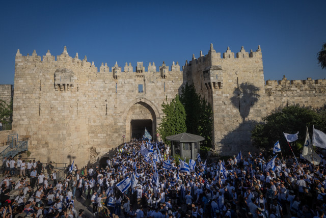  Jewish men hold Israeli flags as they dance at Damascus Gate in Jerusalem's Old City, during Jerusalem Day celebrations, June 5, 2024. (credit: Chaim Goldberg/Flash90)