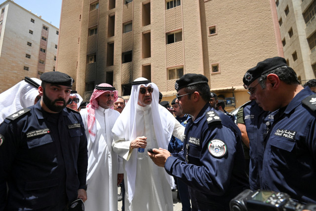  Kuwaiti ministers speaks with police officers in front of a burnt building, following a deadly fire, in Mangaf, southern Kuwait, June 12, 2024 (credit: REUTERS/STRINGER)