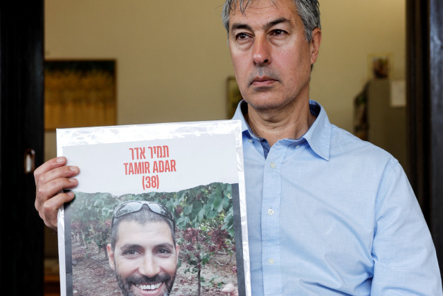 Former Israeli dentist Yuval Bitton, who treated Hamas leader Yahya Sinwar in an Israeli prison, holds a photo of hostage Tamir Adar during an interview in his house in Kibbutz Shoval, Israel, February 5, 2024. (credit: AMIR COHEN/REUTERS)