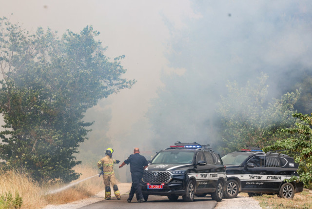  Agentes de policía en el lugar de un incendio provocado por misiles lanzados desde el Líbano, en el bosque de Biriya, en el norte de Israel, el 13 de junio de 2024 (credit: David Cohen/Flash90)