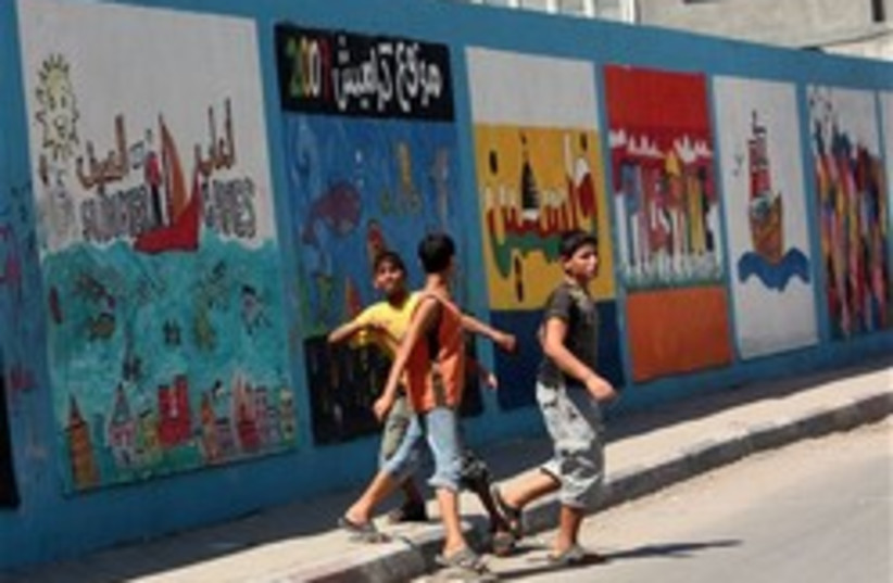 Palestinian youths walk next to a wall of a school (photo credit: AP)