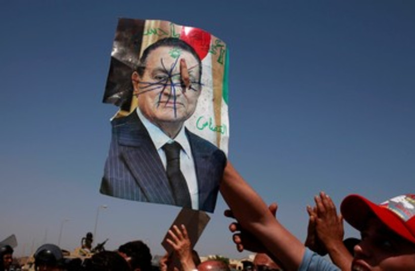 Anti-Mubarak protesters holds defaced picture 370 (photo credit: REUTERS/Suhaib Salem)