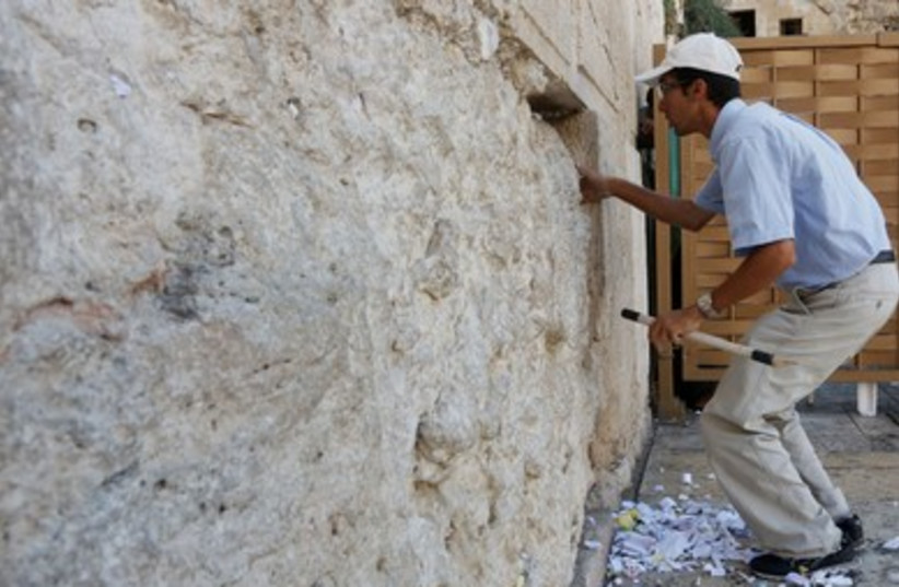 Workers at the Western Wall clean notes out of the crevices