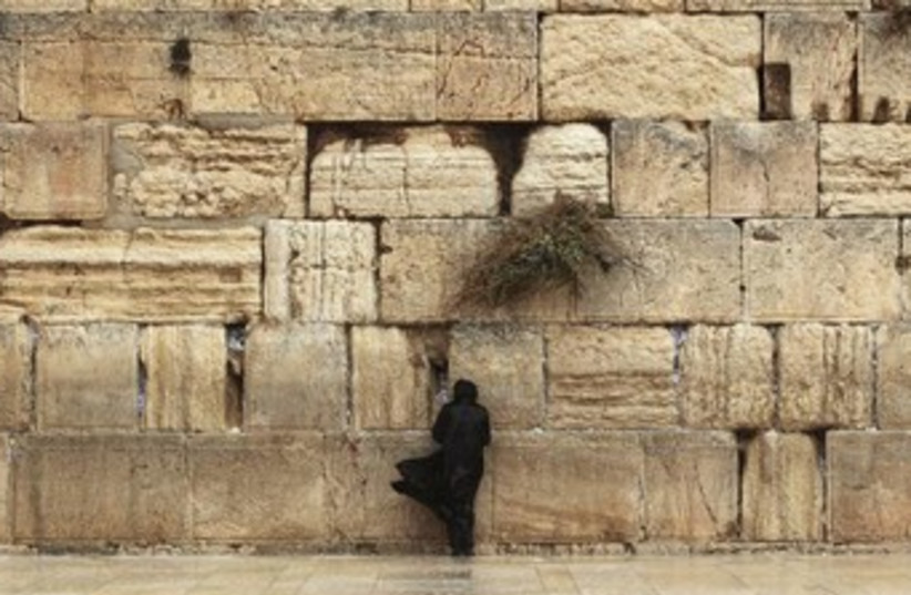 A worshipper braves the weather to pray at the Western Wall 