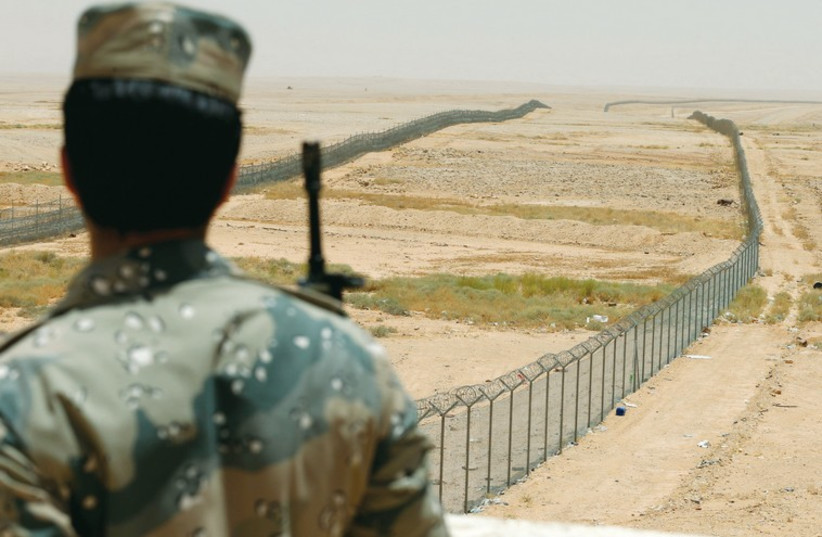 A member of the Saudi border guards force stands guard next to a fence on Saudi Arabia’s northern borderline with Iraq last month. (photo credit: REUTERS)