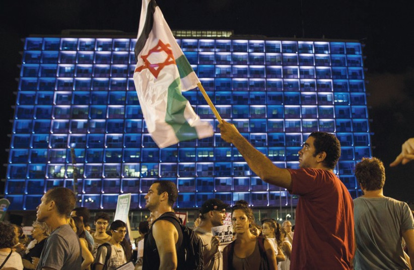 A MAN holds up a flag during a peace rally in Tel Aviv’s Rabin Square  (photo credit: REUTERS)
